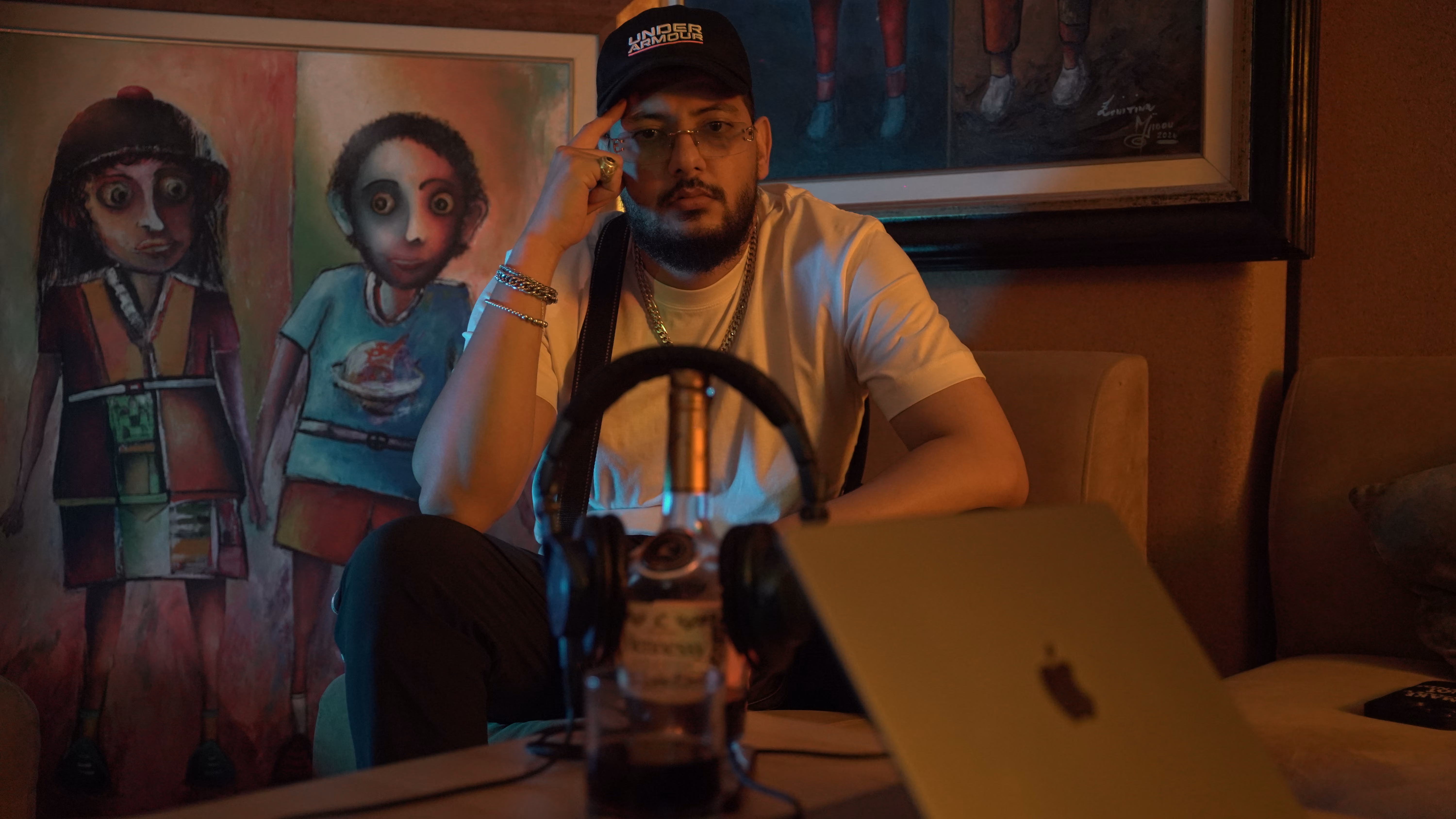 Skizo assis dans le studio, casque et ordinateur posés devant lui